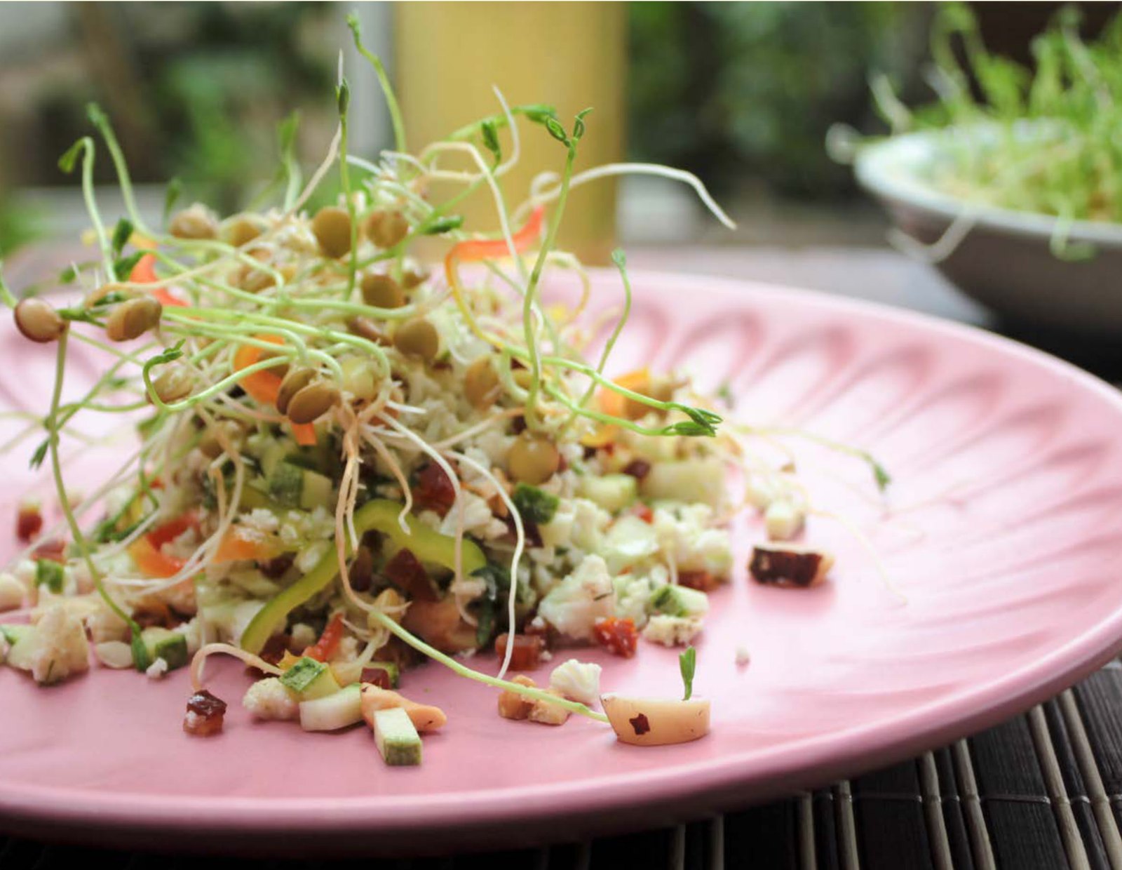 Plato con germinados frescos sobre una ensalada de coliflor y frutos secos